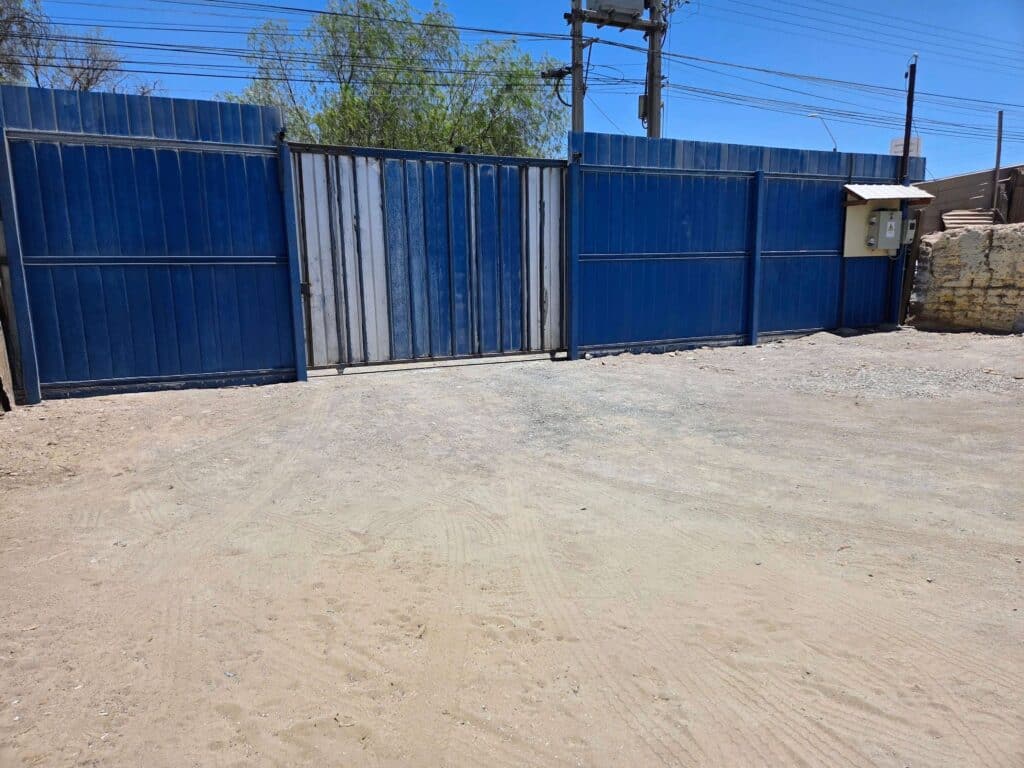 Portón de acceso al estacionamiento privado y seguro de Residencial Baquedano, ideal para camionetas mineras en Baquedano Sierra Gorda, Antofagasta.